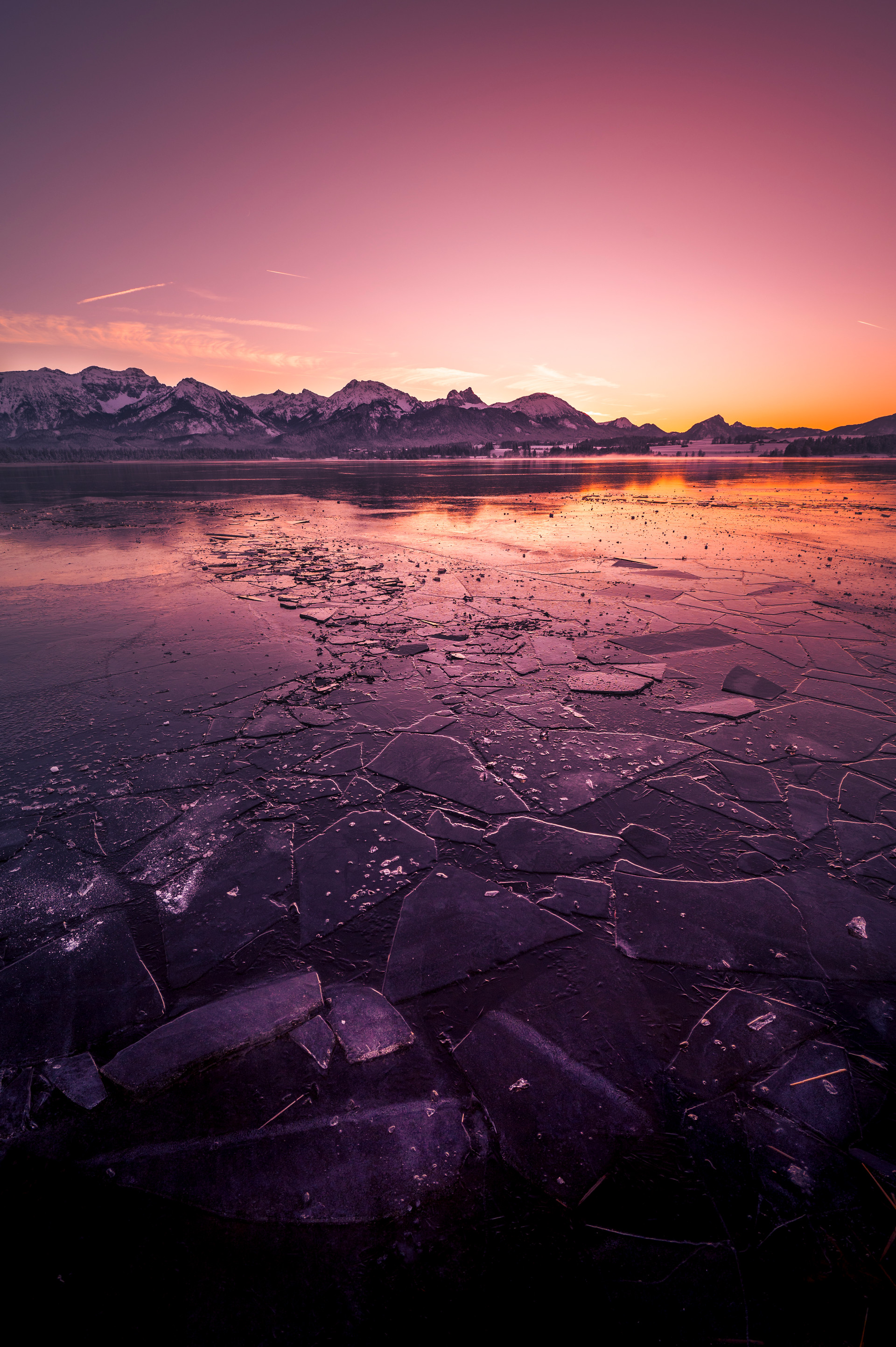 Blick über den zugefrorenen Hopfensee auf die Allgäuer Alpen im farbenprächtigen Sonnenuntergang